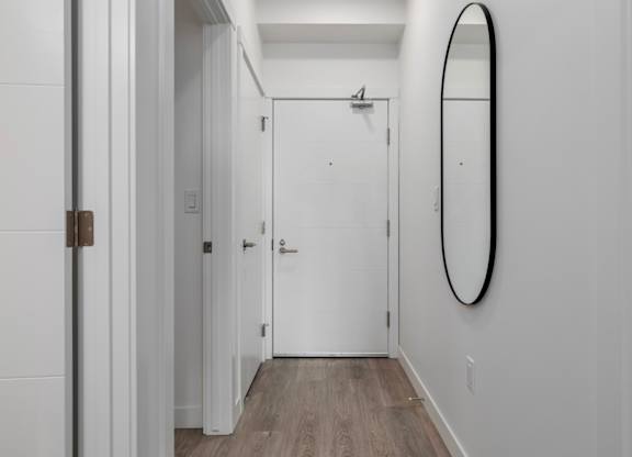 A white door with a mirror on the wall.