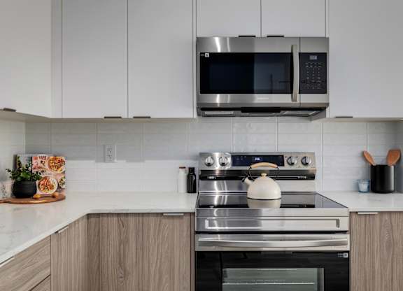 A modern kitchen with a stainless steel oven and microwave above it.