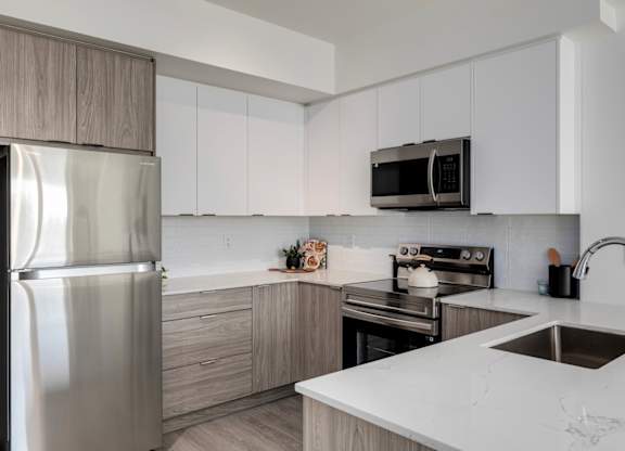 A modern kitchen with a stainless steel refrigerator, microwave, and oven.