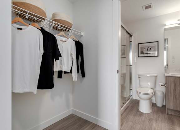 Clothes hanging on a rack in a small bathroom.