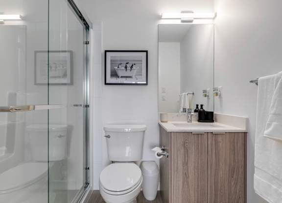 A white toilet sits in a modern bathroom with a glass shower door.