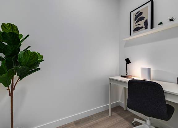 A small desk with a black chair and a lamp on it.