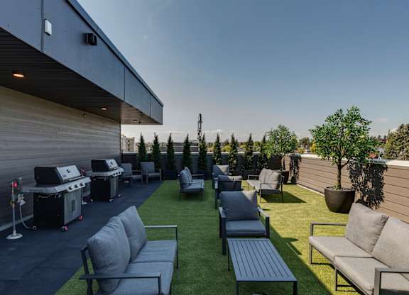 A patio with grey couches and a black table.