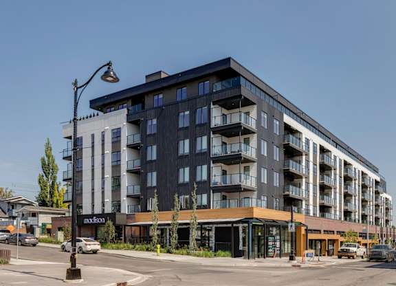 A modern multi-story building with a parking lot in front.