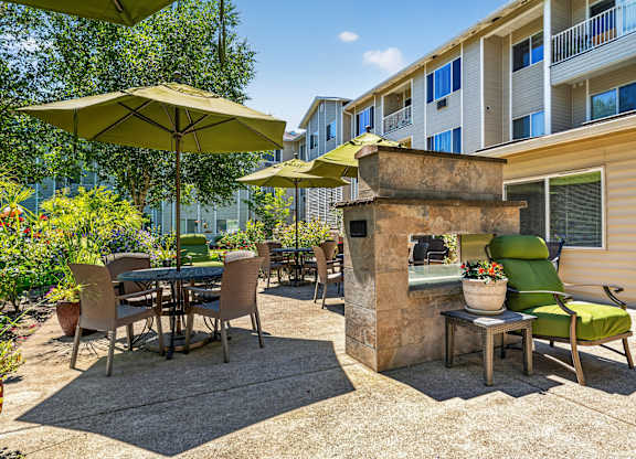 A patio with a table and chairs and a stone fireplace.