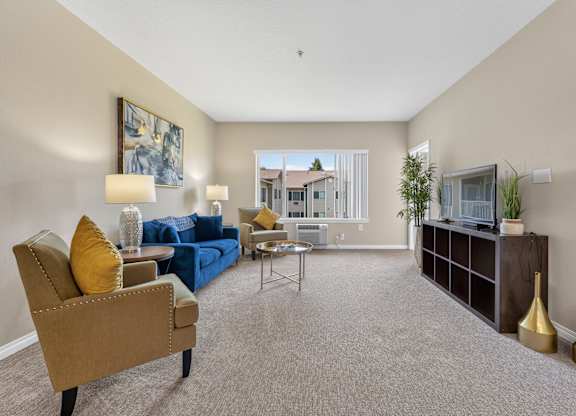 A living room with a blue sofa, a brown armchair, and a television.