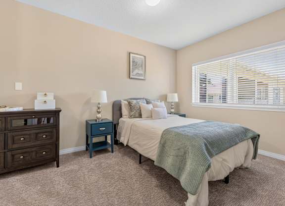 A bedroom with a bed, nightstand, and dresser.