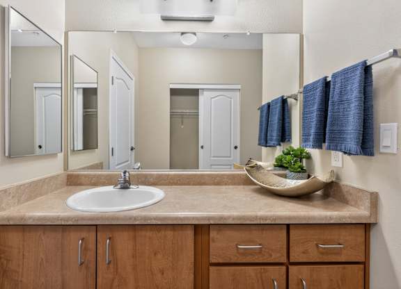 A bathroom with a sink, mirror, and cabinets.