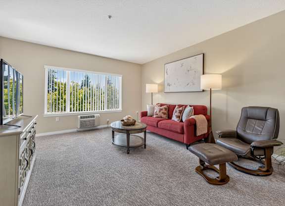A living room with a red couch, a chair, and a coffee table.