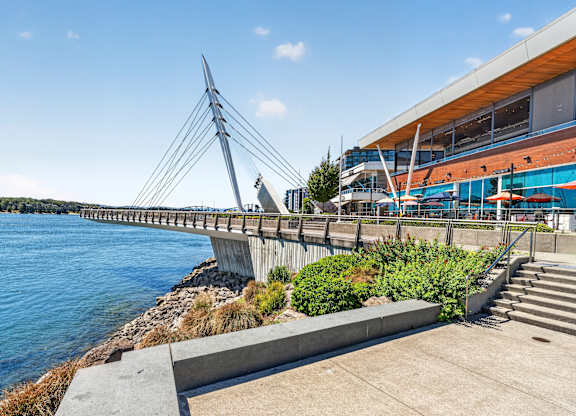 A modern bridge spans across a body of water with a building in the background.