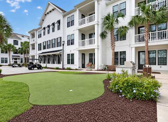 A white building with a green lawn in front.
