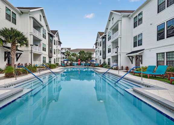 A long rectangular swimming pool in front of apartment buildings.