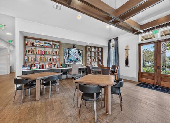A room with a long table and chairs with a bookshelf in the background.