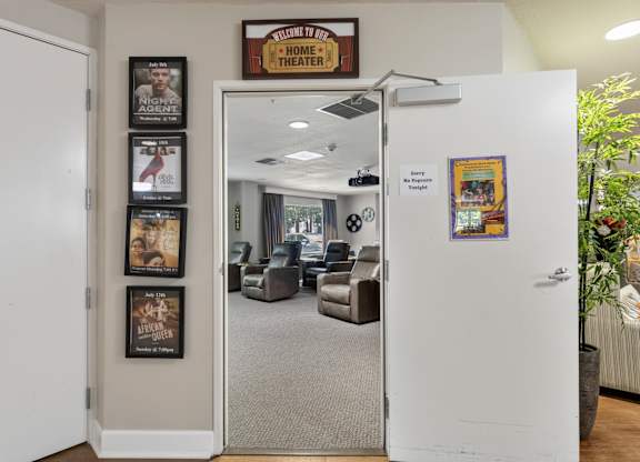 A white door is open to a room with a sign that says "Home Theater".