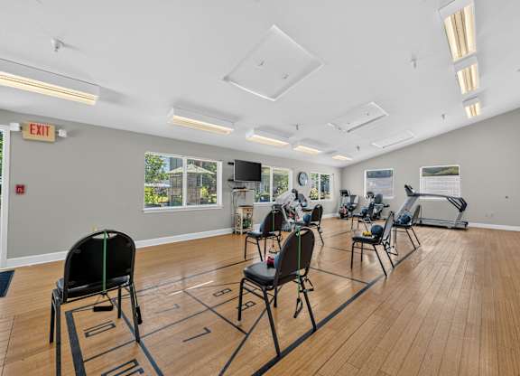 A gym with a row of chairs and a row of exercise bikes.