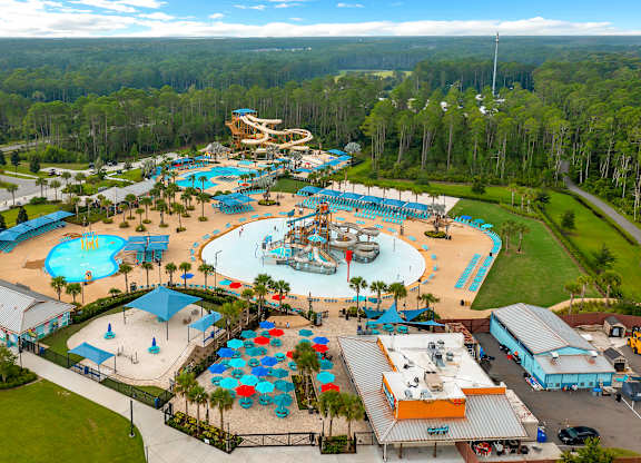 An aerial view of a water park with a large pool and a smaller pool with a slide.