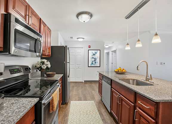 A kitchen with dark wood cabinets and granite countertops.