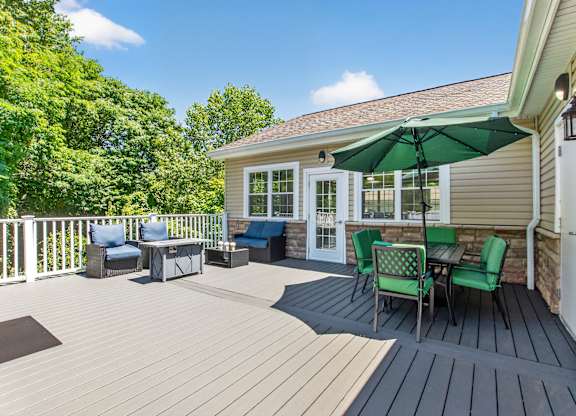 A sunny day on a wooden deck with a green umbrella.