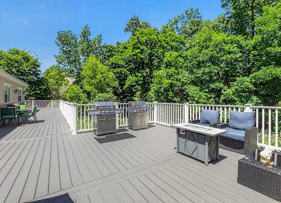 A wooden deck with a table and chairs overlooking a forest.