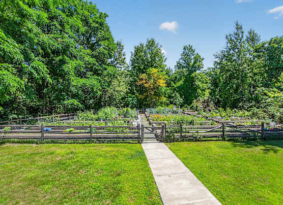 A garden with a fence and a concrete walkway.