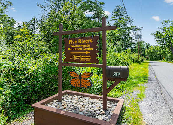 A brown sign with a butterfly on it reads