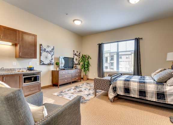 A well-lit bedroom with a bed, couch, and television.