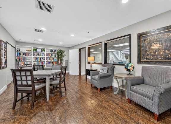 A living room with a couch, chairs, and a bookshelf.