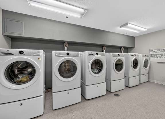 A row of white front load washing machines in a laundromat.