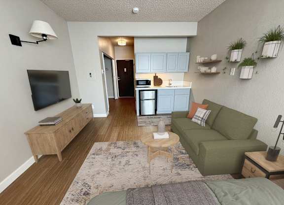 A living room with a couch, a television, and a kitchen area in the background.