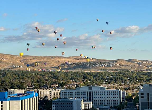 A group of hot air balloons flying over a cityscape.