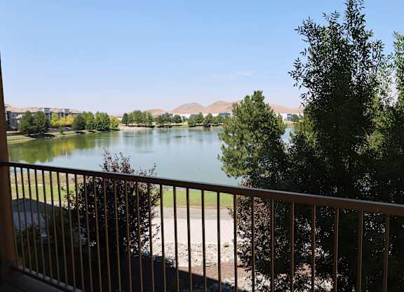 A view of a lake from a balcony with a car parked on the left.
