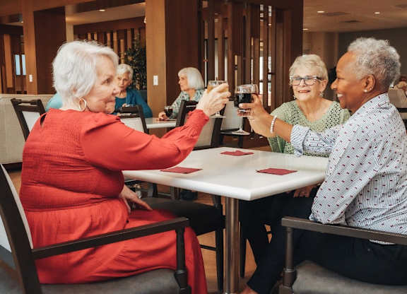 A group of elderly people are sitting around a table playing a card game.
