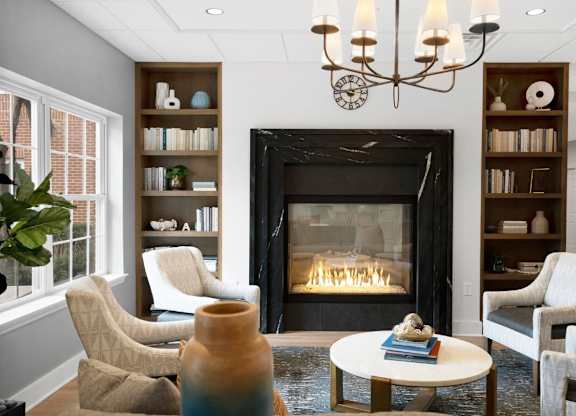 A living room with a fireplace, chairs, and a table.