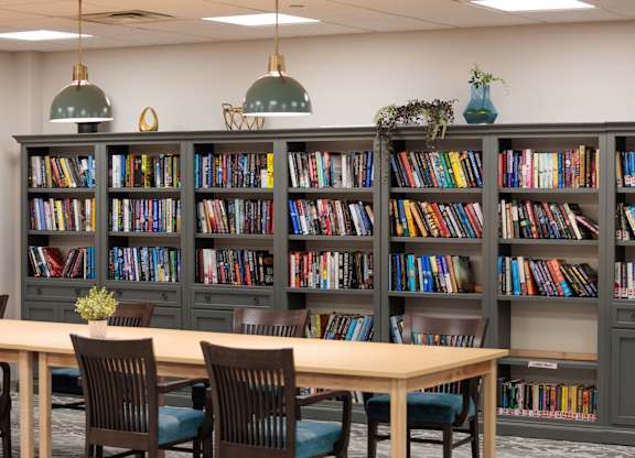 A room with a long table and a bookshelf filled with books.