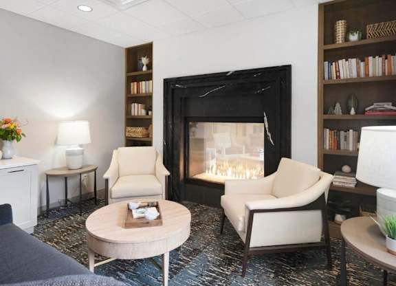 A living room with a fireplace and two chairs.