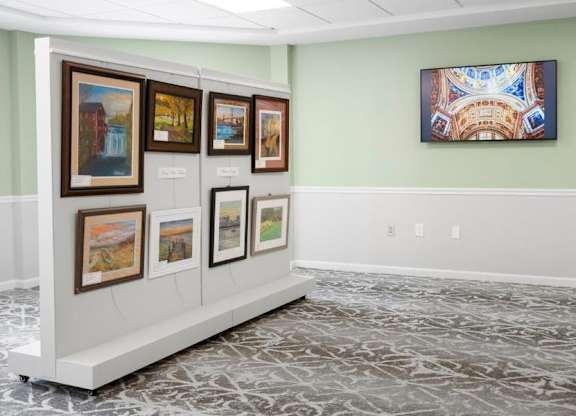 A wall of framed artwork is on display in a room.