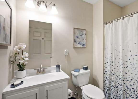 A white bathroom with a sink, toilet, and shower curtain.