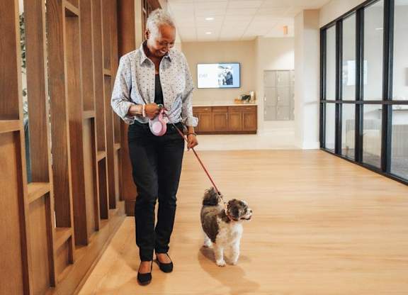 A woman is walking her dog in a hallway.