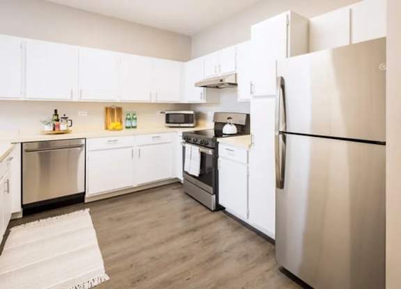 A kitchen with white cabinets and a stainless steel refrigerator.