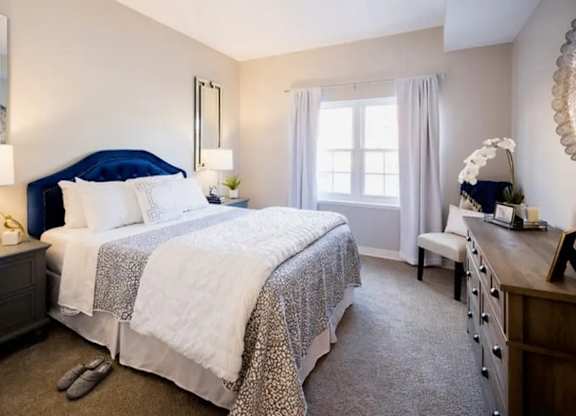 A bedroom with two beds and a nightstand with a lamp.