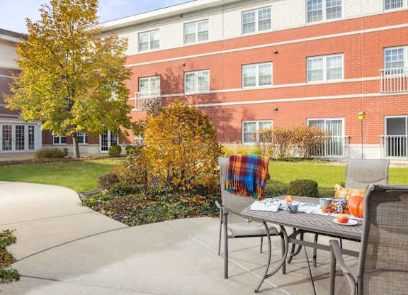 A table with a plaid blanket on it is in front of a brick building.