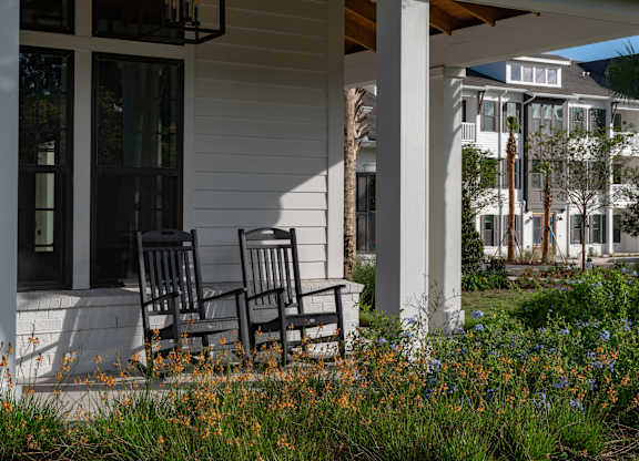Two chairs are on the porch of a white house. at Atwater at Nocatee Apartments, Toledo, 32081