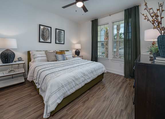 A bedroom with a bed, nightstand, and a ceiling fan. at Atwater at Nocatee Apartments, Florida