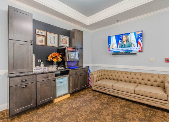 Community lounge with kitchenette and seating at Schuyler Commons Apartments, New York