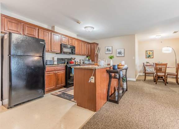 Open kitchen with island and dining space at Schuyler Commons Apartments, Utica, NY
