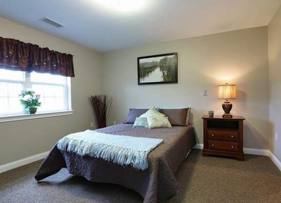 Cozy bedroom with decorative throw pillows at Schuyler Commons Apartments, Utica, 13502