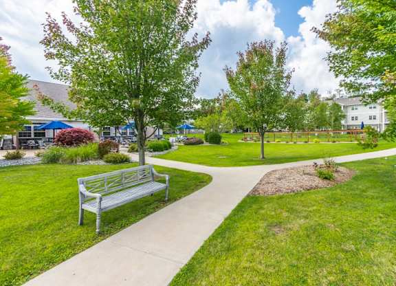 Landscaped walking path with bench and green space at Schuyler Commons Apartments, Utica, NY 13502