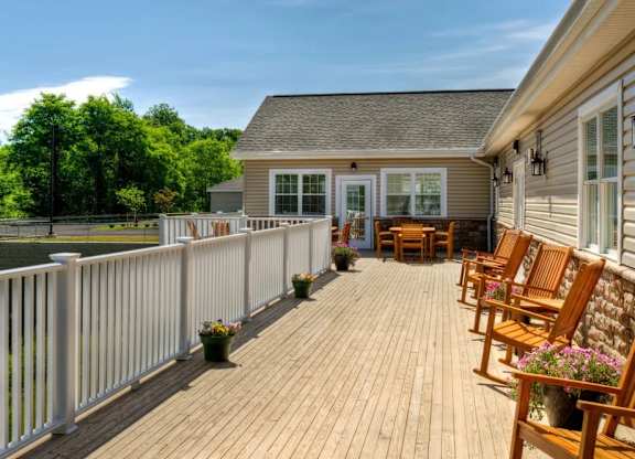 Spacious deck with wooden furniture and white railings at Glenmont Abbey Village, 55+ Apartments, Glenmont, NJ
