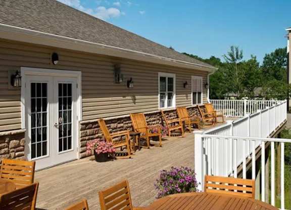 Covered deck with rocking chairs and white railing at Glenmont Abbey Village, 55+ Apartments, Glenmont, 12077