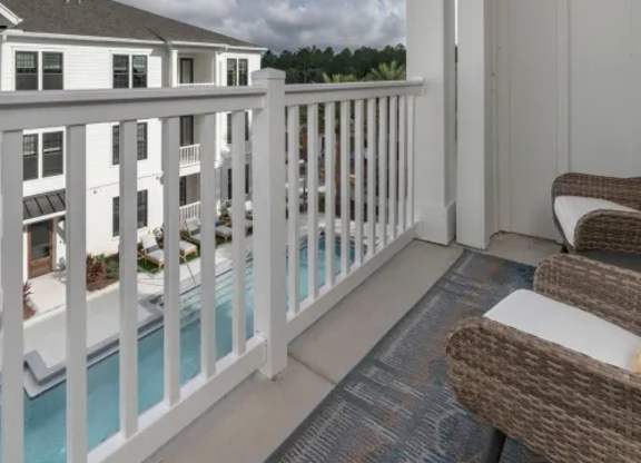A white balcony with a pool and chairs. at Atwater at Nocatee Apartments, Toledo, FL, 32081